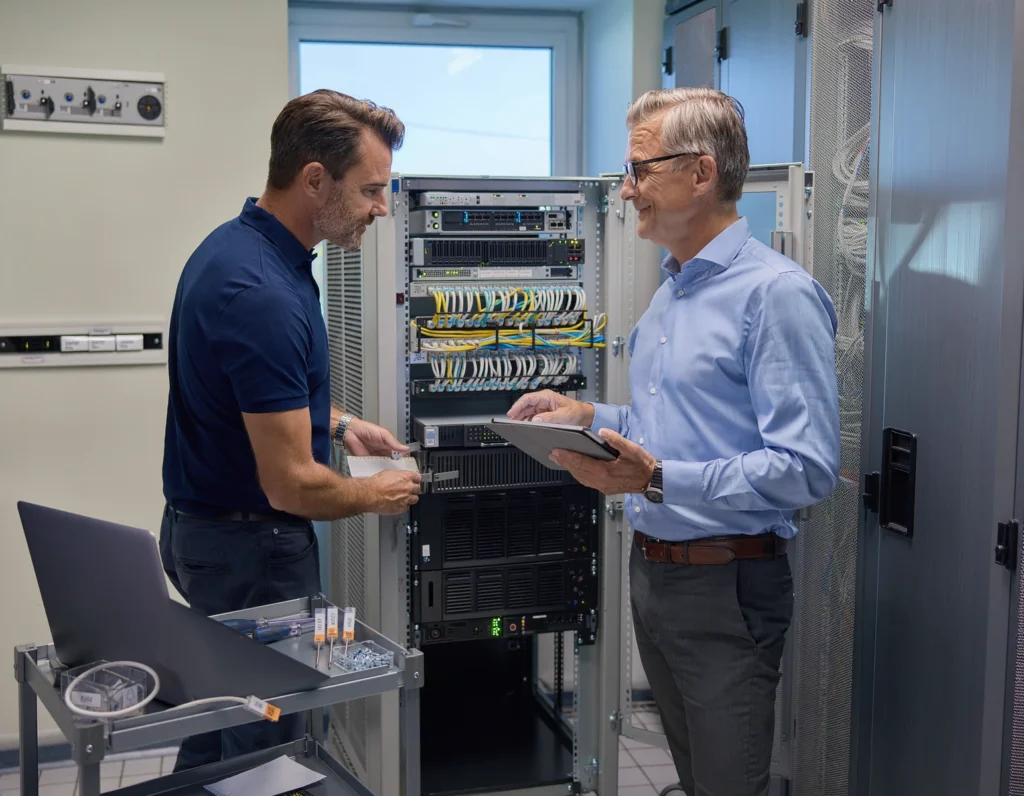 Proxmox-Hochverfügbarkeit: Ein Cluster ersetzt keine Wiederherstellung 4 Zwei Personen prüfen einen geöffneten Serverschrank.